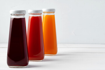 Glass bottles of different juices on white background