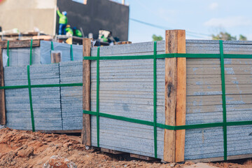 Industrial building cement pressed materials. Concrete block cement brick. Finished products on pallets compactly stacked wooden frame placed on construction site house, rope tape packed open air sky