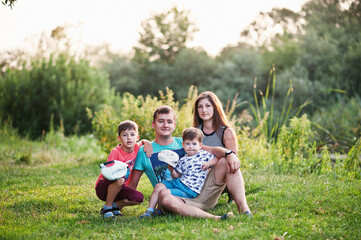 Naklejka na ściany i meble Happy young family: mother, father, two children son on nature having fun.