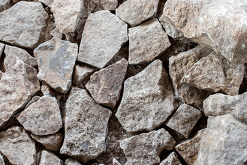 Fragment of a wall of roughly processed gray granite stones. Weathered Stonewall Background from a Castle Wall.