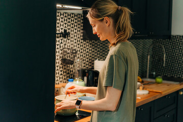 Fototapeta na wymiar A young woman prepares breakfast on the stove in a saucepan.