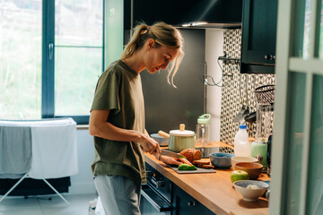 Young woman housewife prepares breakfast in the kitchen.