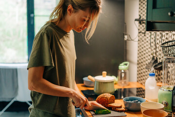 A young woman cooks breakfast in the kitchen.