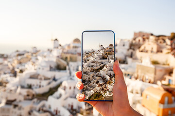 Photographing a landmark using a mobile phone camera. Famous view of Santorini in Greece on a...