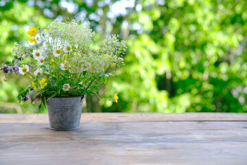 bouquet of wild flowers on table wooden table in garden, beautiful blurred natural landscape in...