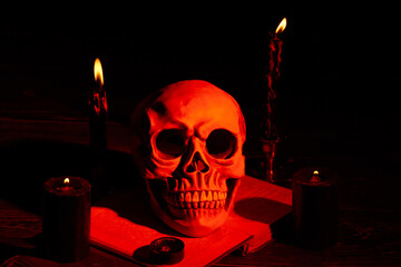 Humans skull and candles with orange light in the dark. Spooky creepy stuff for halloween or...