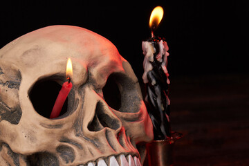 Close-up humans skull with burning candle in its eye. Isolated on black background.