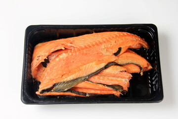 Hot smoked salmon bones on black plastic packaging box, white background