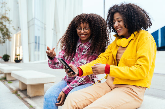 Two young female friends having fun outdoor. Hispanic latin young women with colored casual outfits spending time together. Representation of Carefree and lifestyle concepts	