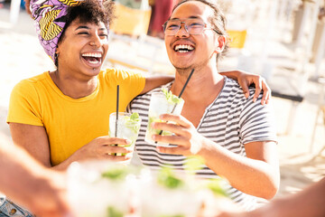 Happy young people toasting mojito drinks at beach cocktail bar - Youth and summertime concept