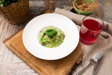 Plate serving of green risotto with basil leaves and cheese. Healthy food. Tender arborio flavored with spinach greens and infused with lamb meat broth