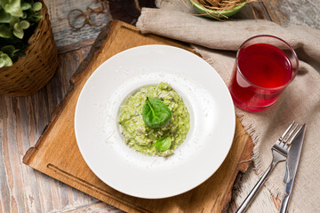 Plate serving of green risotto with basil leaves and cheese. Healthy food. Tender arborio flavored with spinach greens and infused with lamb meat broth