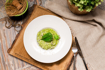 Plate serving of green risotto with basil leaves and cheese. Healthy food. Tender arborio flavored...