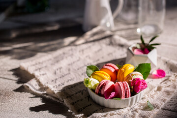 Good morning. Delicious macarons desserts are served on the table in the morning for breakfast. Beautiful light still life with a rose highlight. Baking for breakfast on a light table with copy space