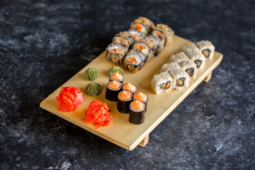 Sushi rolls Japanese delicacies. Japanese traditional rice and fish dishes. Beautiful serving food on a dark background with copy space. A set of delicious goodies.