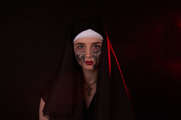 Portrait of a young girl in a hood with creepy face stained with candle wax. Misterious sinister woman.