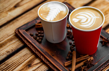 Two paper cups of cappuccino coffee on woden table background