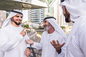 Fototapeta na wymiar Three business men walking in Dubai wearing traditional emirati clothes