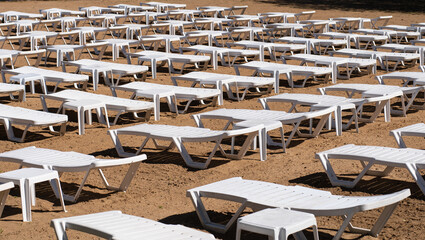 White sunbeds on empty sandy beach with no people 