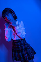 Fototapeta premium Cheerful ecstatic young woman in hoodie keeping eyes closed and laughing while enjoying music in headphones, studio shot 