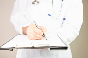 Close-up view of female doctor hands filling patient registration form. Healthcare and medical concept