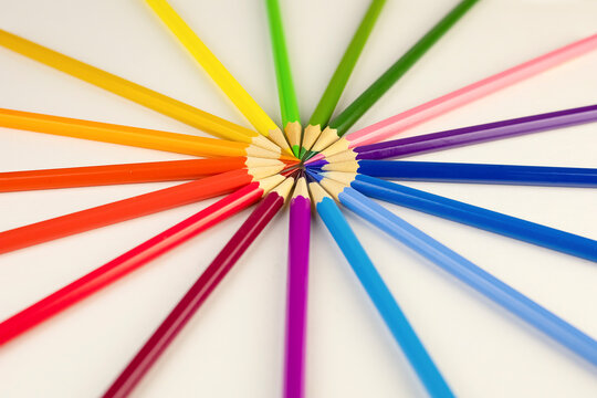 Colored multi-colored bright pencils are laid out in a circle on a white background with copy space. Closeup of colored pencils. Back to school.