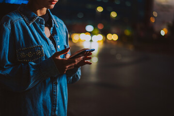 Image of a young woman using mobile phone on the street.