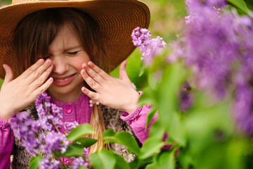 Child with pollen allergy. Girl sneezing and blowing nose because of seasonal allergy. Spring allergy concept. Flowering bushes and trees in background. Child allergy - obrazy, fototapety, plakaty