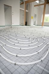 Shot of construction site in a loft where underfloor heating has just been installed, white pipes on grey mat