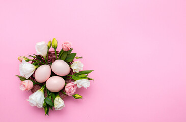 Easter background with Easter eggs and spring flowers. Top view with copy space. Nest with eggs decorated with beautiful flowers on a pink background.