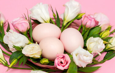 Easter background with Easter eggs and spring flowers. Top view with copy space. Nest with eggs decorated with beautiful flowers on a pink background.