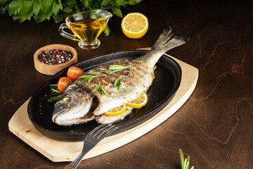 roasted dorado fish with lemon on dark wooden background. Copy space.
