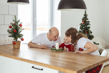 Baby child with hearing aid and cochlear implant having fun with parents in christmas room. Deaf , diversity and health concept