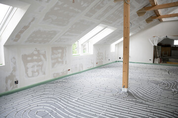 Shot of construction site in a loft where underfloor heating has just been installed, white pipes on grey mat