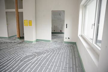 Shot of construction site in a loft where underfloor heating has just been installed, white pipes on grey mat