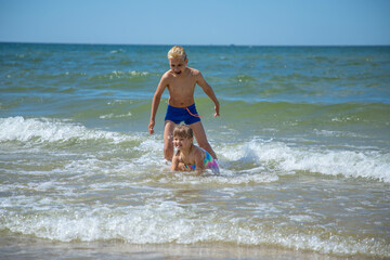 Girl and boy of having fun in water on beach and splashing