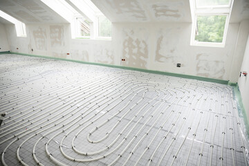Shot of construction site in a loft where underfloor heating has just been installed, white pipes...