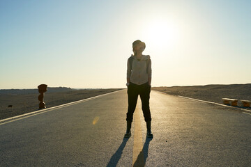 asian backpacker traveler standing in the middle of a road in gobi desert