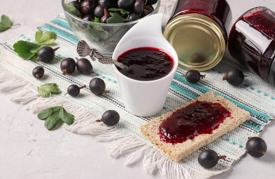 Homemade thick yoshta jam is spread on bread and served for breakfast, also jam in bowl and glass jars