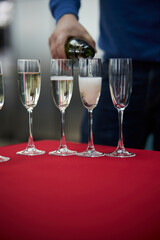 The waiter pours champagne. A man pours champagne into glasses.