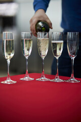 The waiter pours champagne. A man pours champagne into glasses.