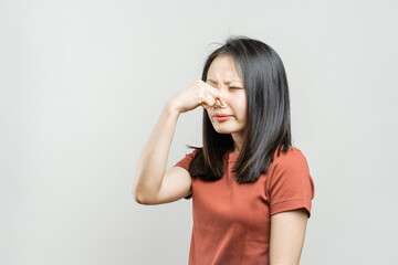 Portrait of a Korean girl on a gray background. Asian girl covered her nose from the smell