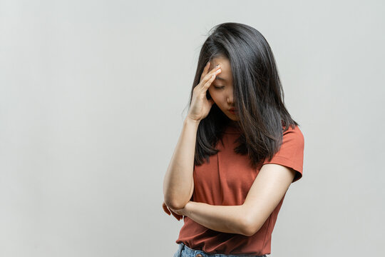 Portrait of a Korean girl on a gray background. Asian girl in depression