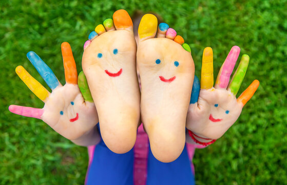 Feet of a child on the grass with a painted smile. Selection focus.