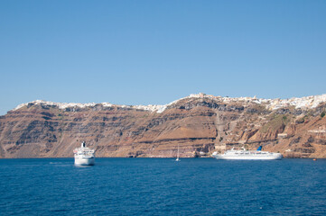 Overview of Santorini's coastal cliffs as seen from a boat on the water.