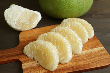 Delectable Peeled Fresh Pomelo Fruit Segments Lined Up on Wooden Cutting Board