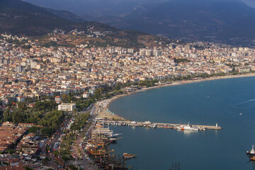Obraz premium Turkey, Alanya, 30.08.2021: The city of Alanya (Turkey) and the Mediterranean Sea from a bird's eye view. Densely populated city. Travel to Turkey. Sea port. Türkiye 