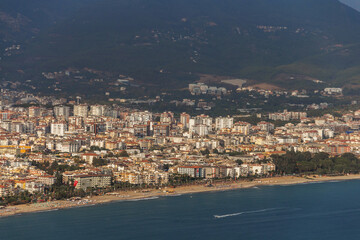 Turkey, Alanya, 30.08.2021: The city of Alanya (Turkey) and the Mediterranean Sea from a bird's eye view. Densely populated city and mountains from above. Travel to Turkey.