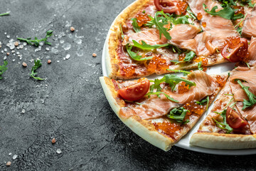 salmon Italian Pizza with red caviar, tomatoes and aragula ready to eat on a dark background. banner, menu, recipe place for text, top view