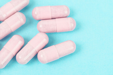 Pink capsule pills on blue background.